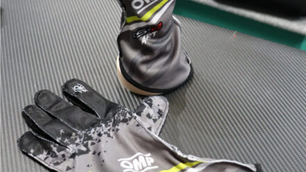 A pair of anthracite OMP KS-2 Art kart gloves on a carbon-effect counter in the GSM Performance showroom