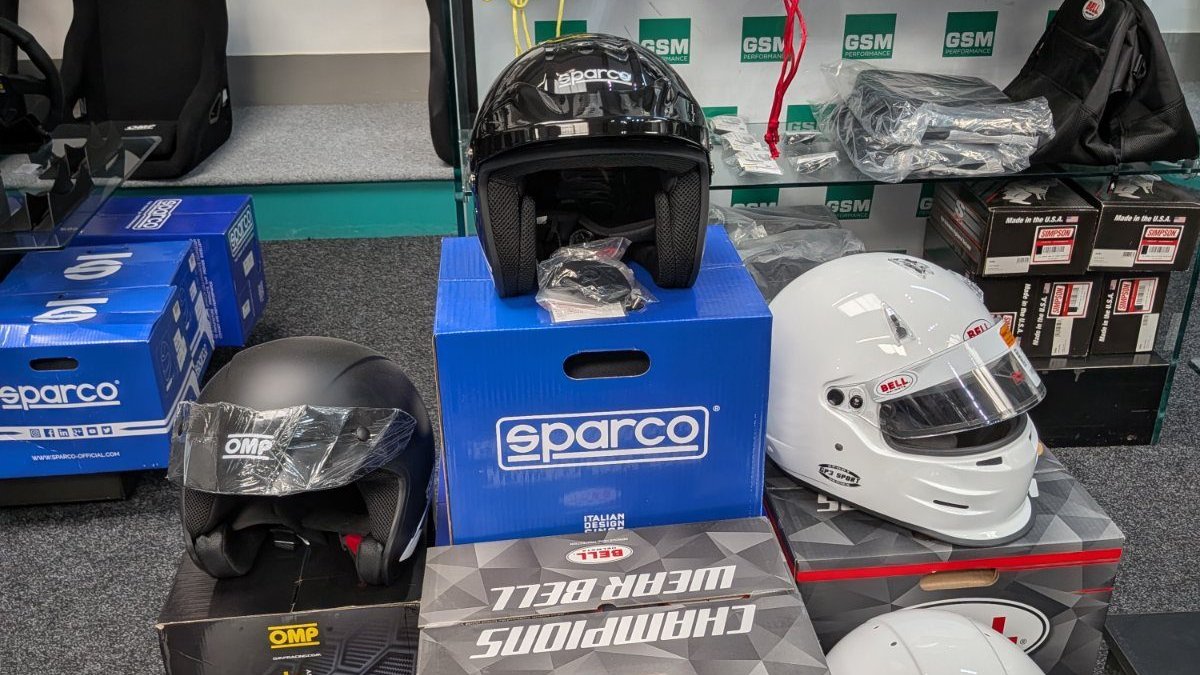 The black and grey Sparco J-Pro on its box in the GSM Performance showroom, alongside OMP, Bell and Simpson helmets on the display bench