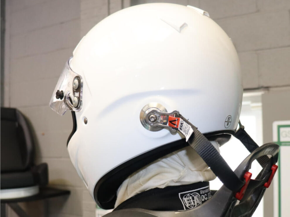 White Sparco Air Pro RF-5W helmet from the side, with the HANS tether clipped to its post