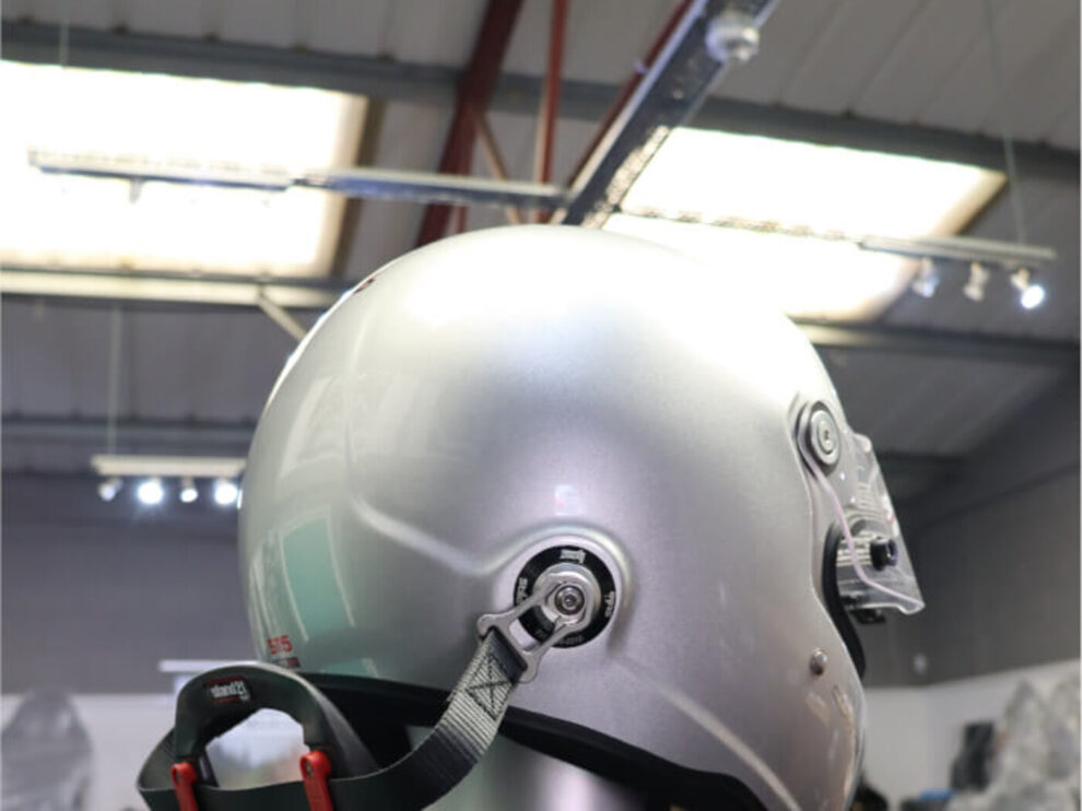 Silver Stilo ST5 FN helmet from the side, with the HANS tether clipped to its post