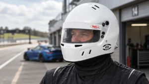 Driver wearing a white Bell GT6 Pro full-face helmet with a clear visor in a circuit pit lane
