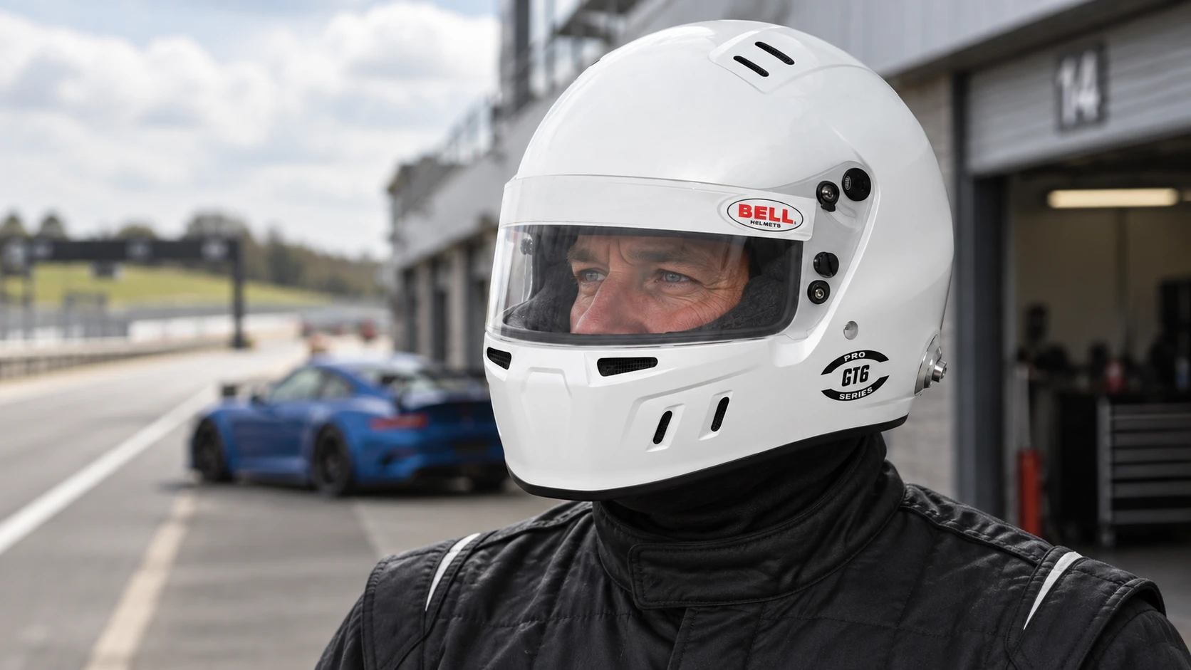 Driver wearing a white Bell GT6 Pro full-face helmet with a clear visor in a circuit pit lane