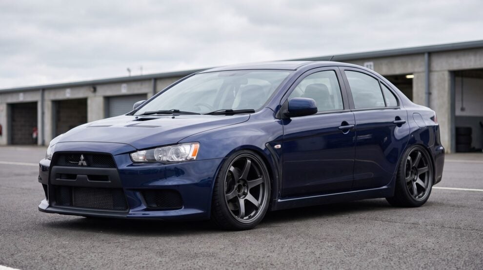 Mitsubishi Lancer Evolution X CZ4A on coilovers, parked in a pit lane, arches closed, dark aftermarket wheels