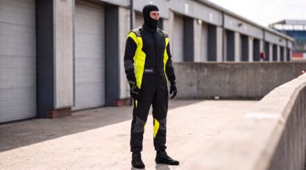Driver in a Sparco Futura black and fluorescent yellow race suit in a British pit lane