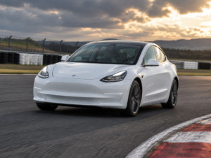 White Tesla Model 3 sedan cornering on a race circuit